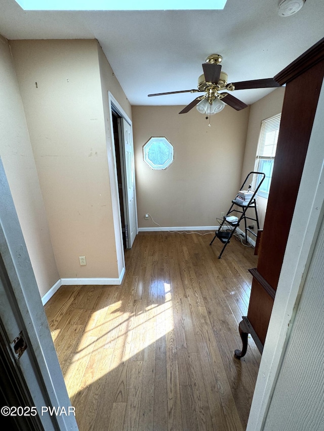 interior space with light hardwood / wood-style floors, ceiling fan, a skylight, and a closet