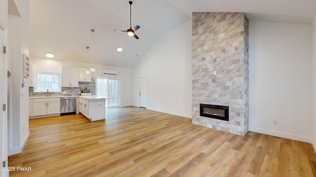 kitchen featuring pendant lighting, dishwasher, white cabinetry, a fireplace, and decorative backsplash