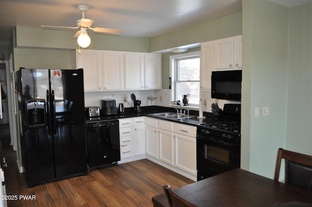 kitchen with white cabinets, dark countertops, dark wood-style flooring, black appliances, and a sink