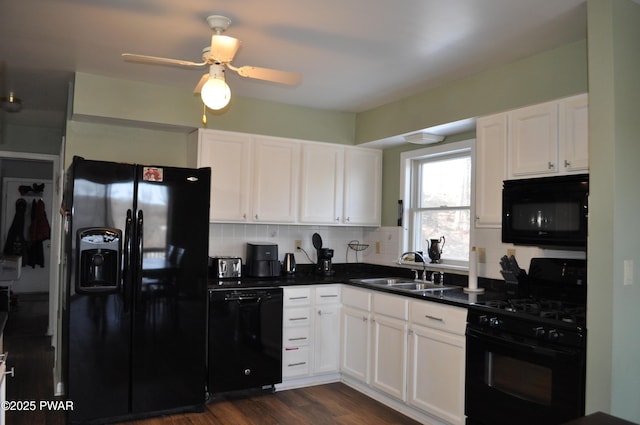 kitchen with black appliances, dark countertops, a sink, and white cabinets