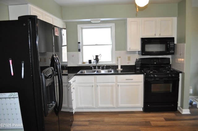 kitchen with dark countertops, white cabinetry, a sink, and black appliances