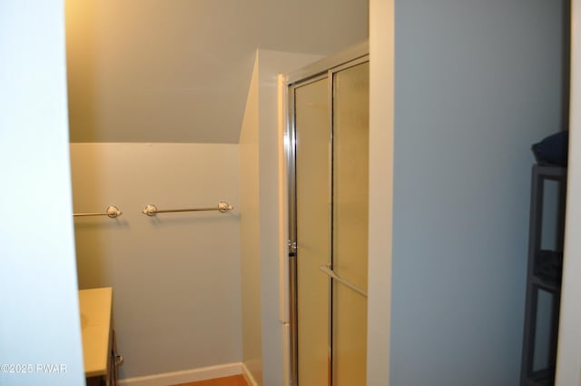 bathroom featuring lofted ceiling, baseboards, an enclosed shower, and vanity