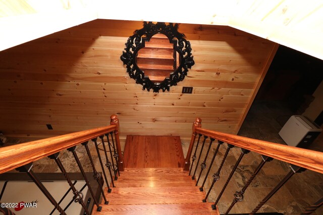 stairway with hardwood / wood-style flooring and wooden walls