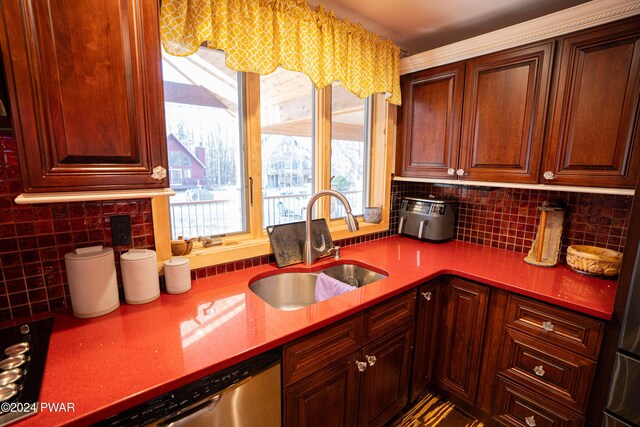 kitchen featuring decorative backsplash, light stone countertops, cooktop, sink, and dishwasher