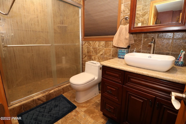 bathroom with vanity, toilet, a shower with door, and tile walls