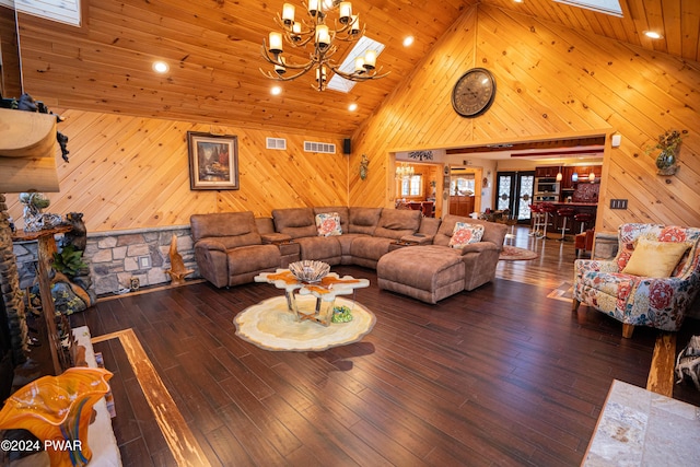 living room featuring a skylight, high vaulted ceiling, a notable chandelier, dark hardwood / wood-style floors, and wood walls