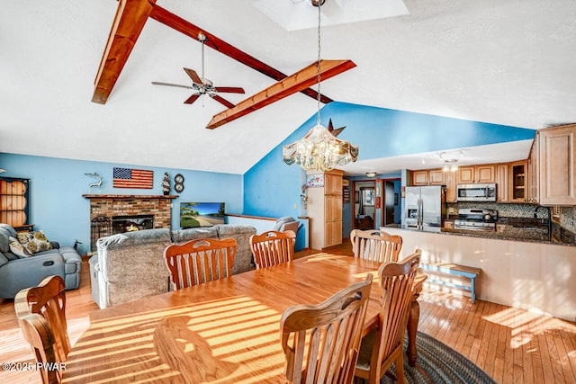 dining room with a fireplace, lofted ceiling with beams, sink, ceiling fan, and light hardwood / wood-style floors