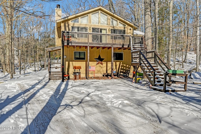 snow covered rear of property with a deck