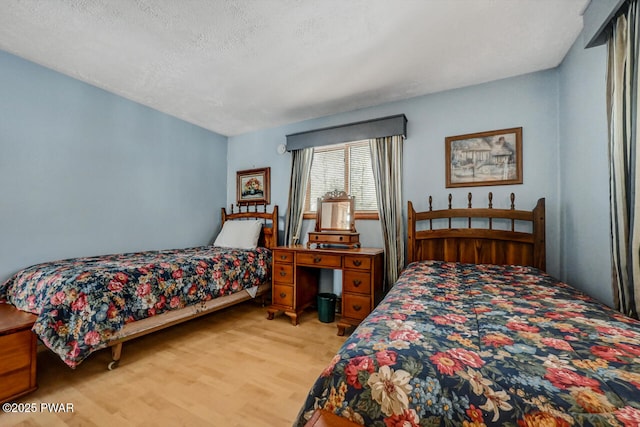 bedroom with light hardwood / wood-style flooring and a textured ceiling