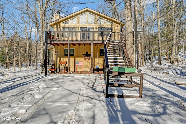 snow covered house featuring a wooden deck