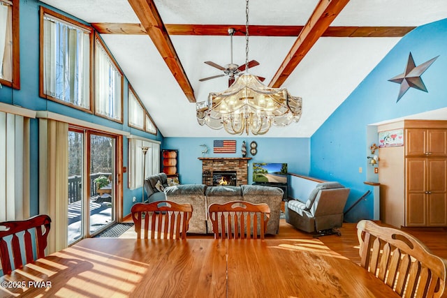 dining area with a brick fireplace, vaulted ceiling with beams, ceiling fan, and light wood-type flooring