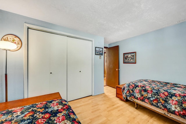 bedroom featuring a textured ceiling, light wood-type flooring, and a closet