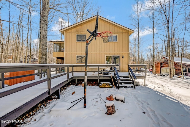 snow covered rear of property with a wooden deck