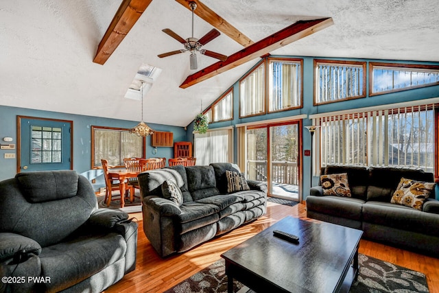 living room featuring beamed ceiling, a ceiling fan, a textured ceiling, and wood finished floors