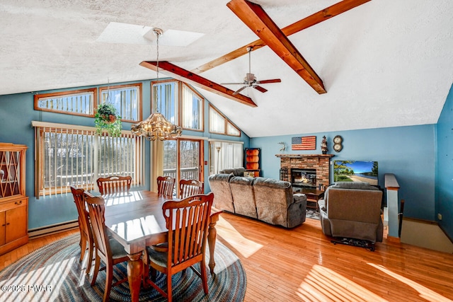 dining room featuring hardwood / wood-style flooring, a baseboard radiator, lofted ceiling with skylight, and a wealth of natural light