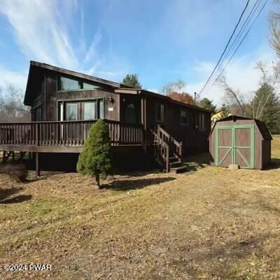 rear view of house with a wooden deck and a shed