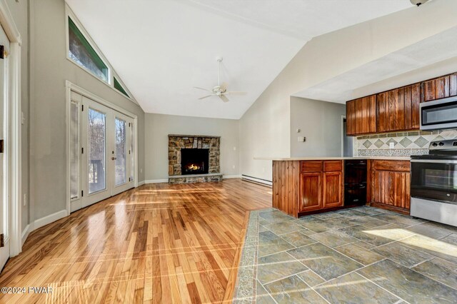 kitchen with french doors, stainless steel appliances, a baseboard radiator, tasteful backsplash, and a stone fireplace