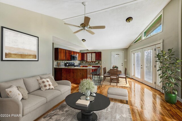 living room featuring hardwood / wood-style flooring, ceiling fan, lofted ceiling, and french doors