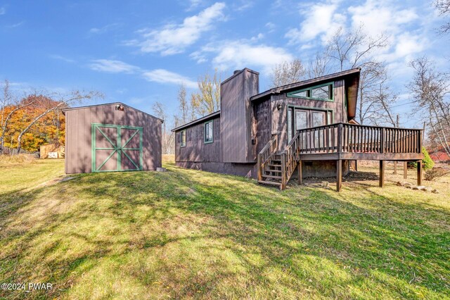 back of property featuring a lawn, a wooden deck, and an outdoor structure