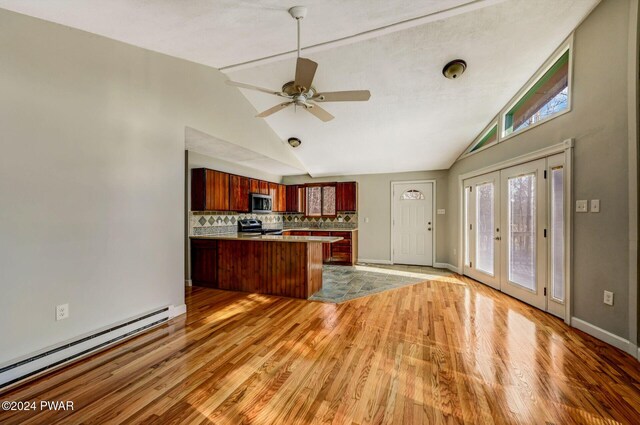 kitchen featuring decorative backsplash, appliances with stainless steel finishes, kitchen peninsula, ceiling fan, and a baseboard heating unit