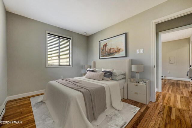 bedroom featuring a baseboard heating unit and light hardwood / wood-style flooring