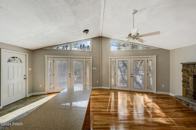 interior space featuring a fireplace, french doors, vaulted ceiling, and ceiling fan