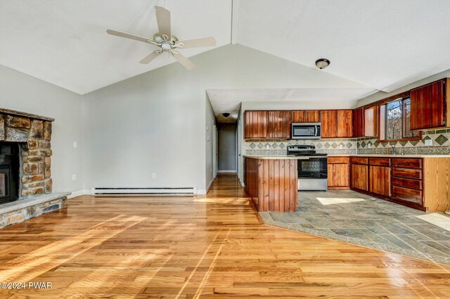 kitchen with backsplash, a baseboard heating unit, a stone fireplace, vaulted ceiling, and appliances with stainless steel finishes