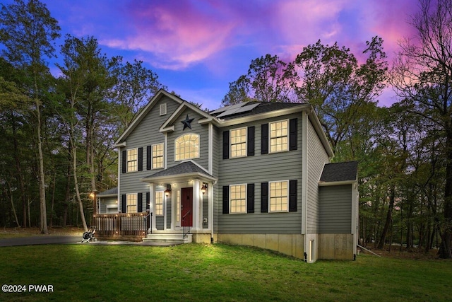 colonial house featuring a lawn and solar panels