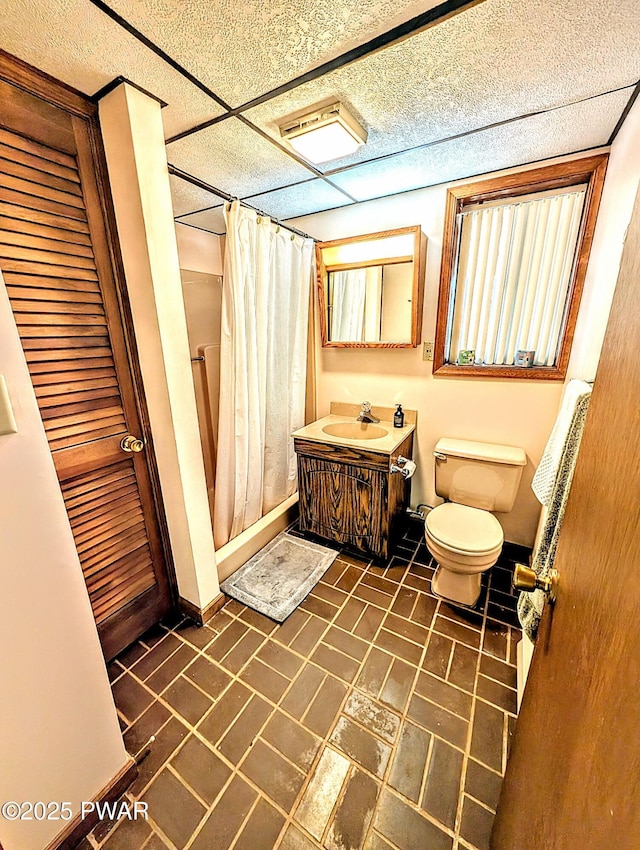 bathroom featuring brick floor, vanity, toilet, a shower with shower curtain, and baseboards