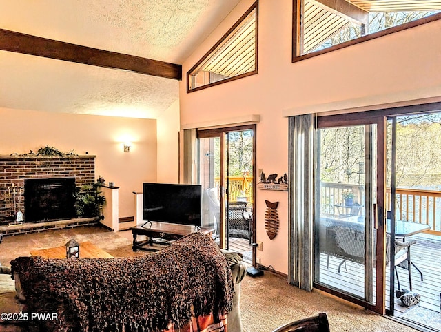 carpeted living area featuring a textured ceiling, a healthy amount of sunlight, beam ceiling, and a fireplace
