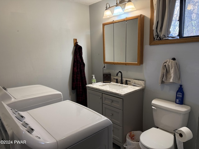 bathroom featuring independent washer and dryer, vanity, and toilet