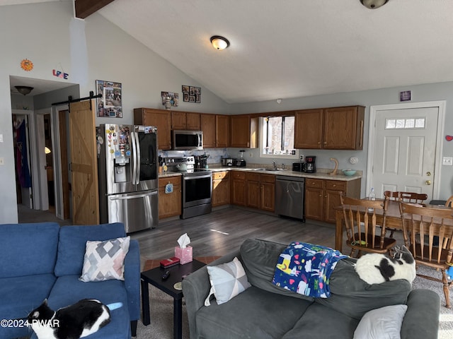 kitchen featuring backsplash, stainless steel appliances, sink, a barn door, and vaulted ceiling with beams