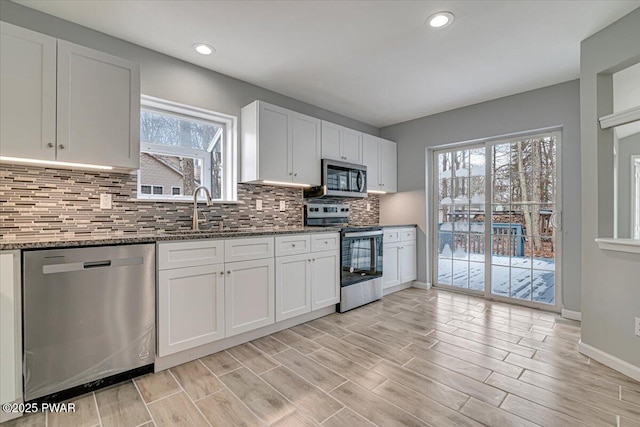 kitchen featuring dark stone countertops, white cabinetry, sink, and appliances with stainless steel finishes