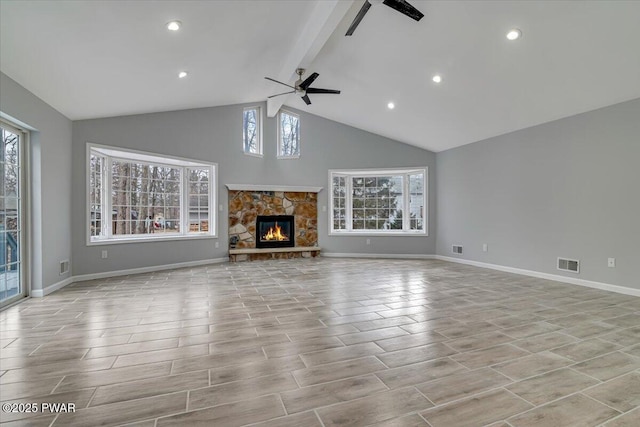 unfurnished living room with a stone fireplace, ceiling fan, beamed ceiling, and high vaulted ceiling