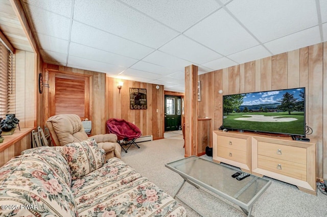 carpeted living room featuring wood walls and a paneled ceiling