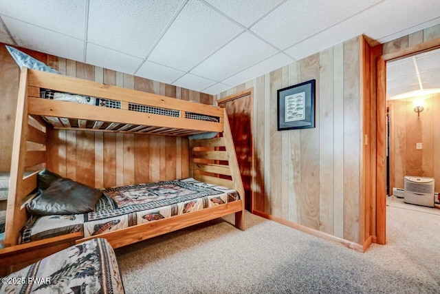 bedroom with carpet, a paneled ceiling, and wooden walls