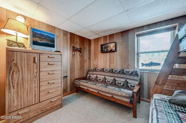 sitting room with carpet flooring, wooden walls, and a drop ceiling