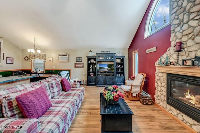 living room featuring an AC wall unit, a notable chandelier, a fireplace, and wood finished floors