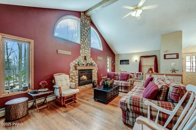 living area with high vaulted ceiling, a stone fireplace, a baseboard radiator, wood finished floors, and beam ceiling