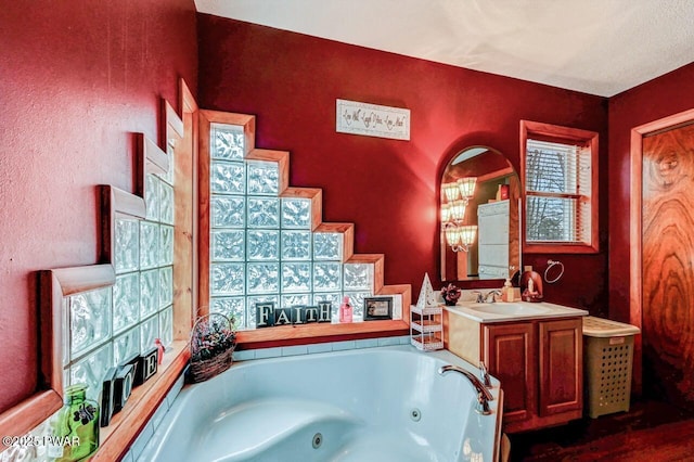 full bathroom featuring a tub with jets and vanity