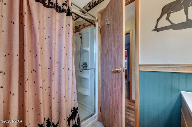 bathroom featuring a stall shower and a wainscoted wall