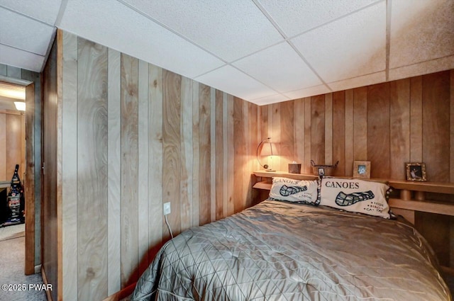 bedroom with a paneled ceiling and wooden walls