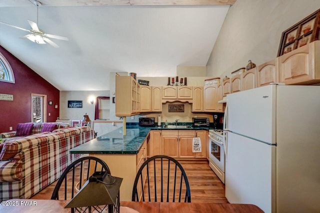 kitchen featuring white appliances, dark countertops, lofted ceiling, wood finished floors, and light brown cabinetry