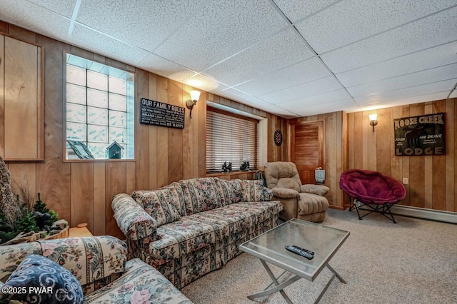 living room featuring a baseboard heating unit, carpet, a drop ceiling, and wood walls