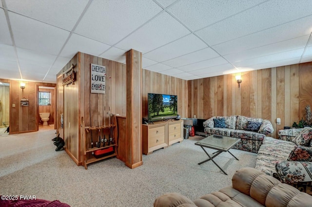 carpeted living room with a drop ceiling and wooden walls