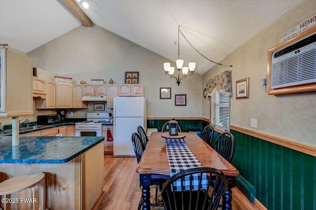 kitchen with beam ceiling, wainscoting, a sink, white appliances, and under cabinet range hood