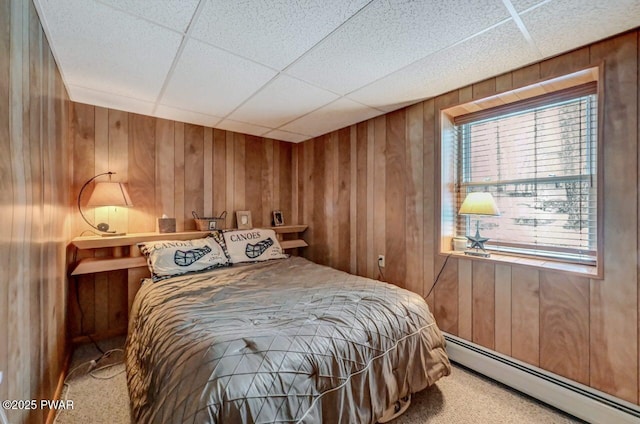 bedroom featuring wood walls, a baseboard heating unit, and carpet flooring