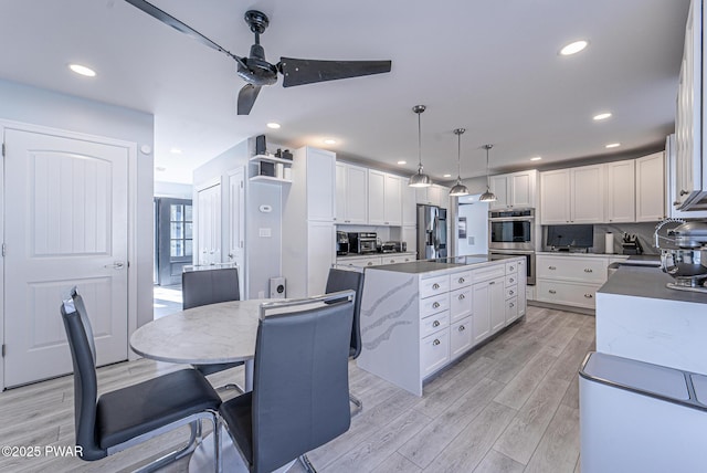 kitchen with light wood-style flooring, white cabinetry, stainless steel appliances, and a center island