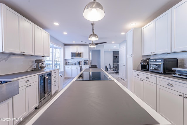 kitchen featuring black electric stovetop, wine cooler, white cabinetry, decorative backsplash, and stainless steel microwave