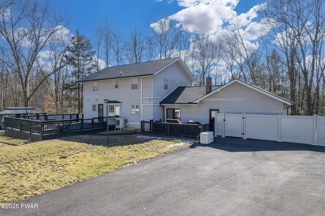 view of side of property with a gate, roof with shingles, a yard, and a deck